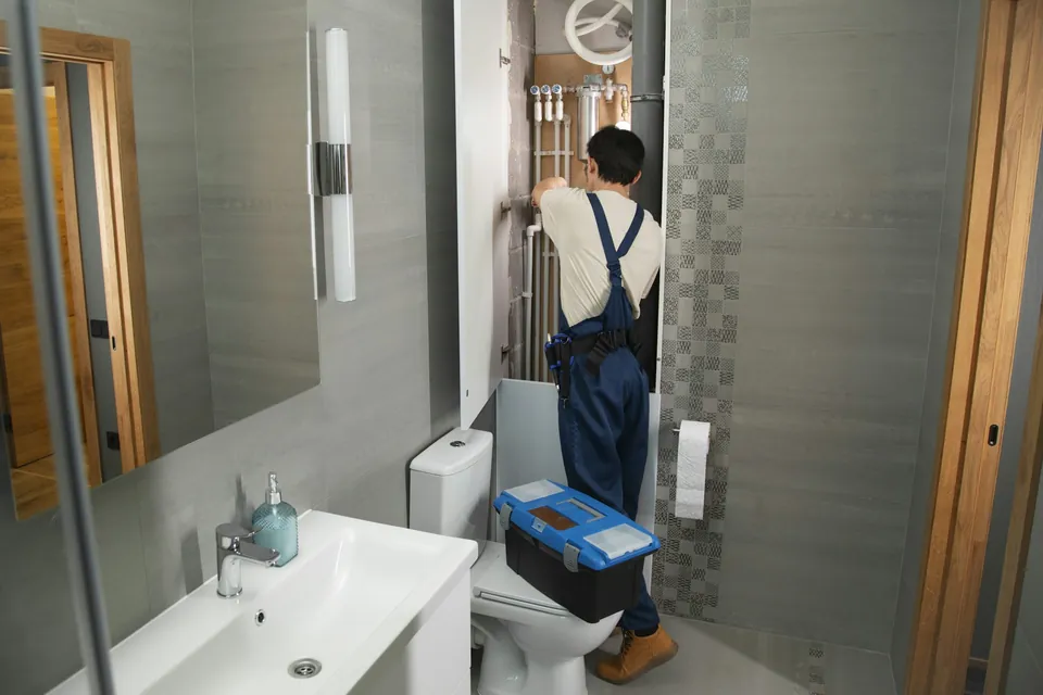 Gasfíter revisando la instalación de un baño con su caja de herramientas
