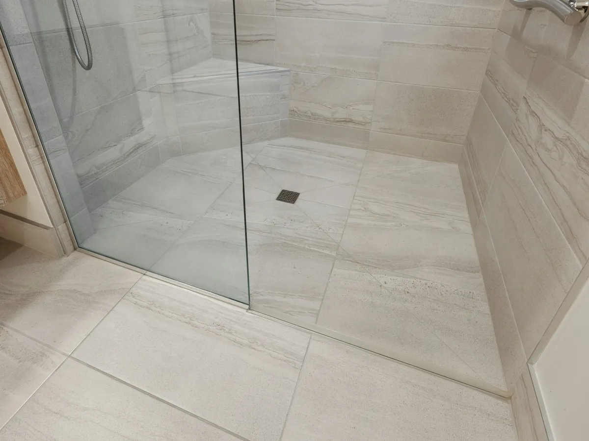 Piso de ducha con cerámica gris y mampara de vidrio